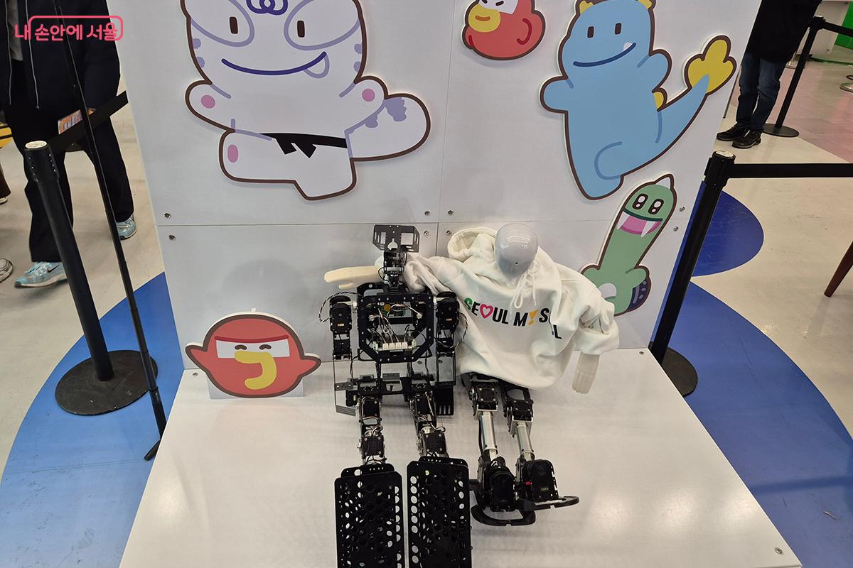 '서울 마이 소울' 로고가 새겨진 옷을 입고 있는 로봇과 해치와 친구들의 모습이 잘 어울린다.