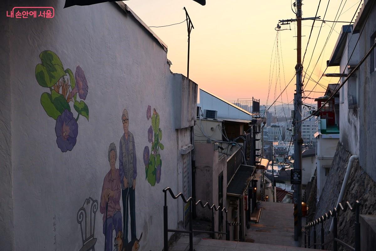 해 질 녘 노을을 배경으로 소박한 일상을 담은 벽화가 골목길의 정겨운 운치를 완성한다. &copy;이봉덕
