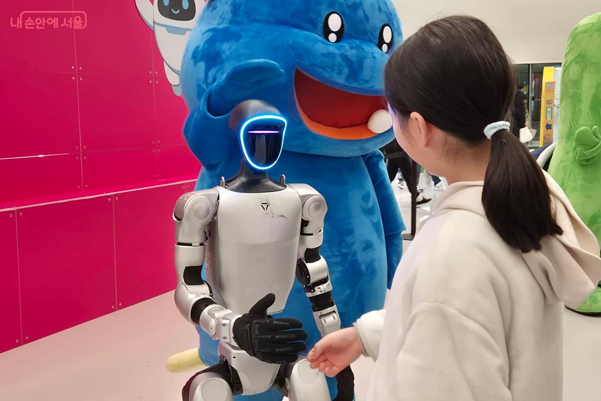 휴머노이드 로봇과 어린 아이가 악수를 하고 있다. ⓒ마가은