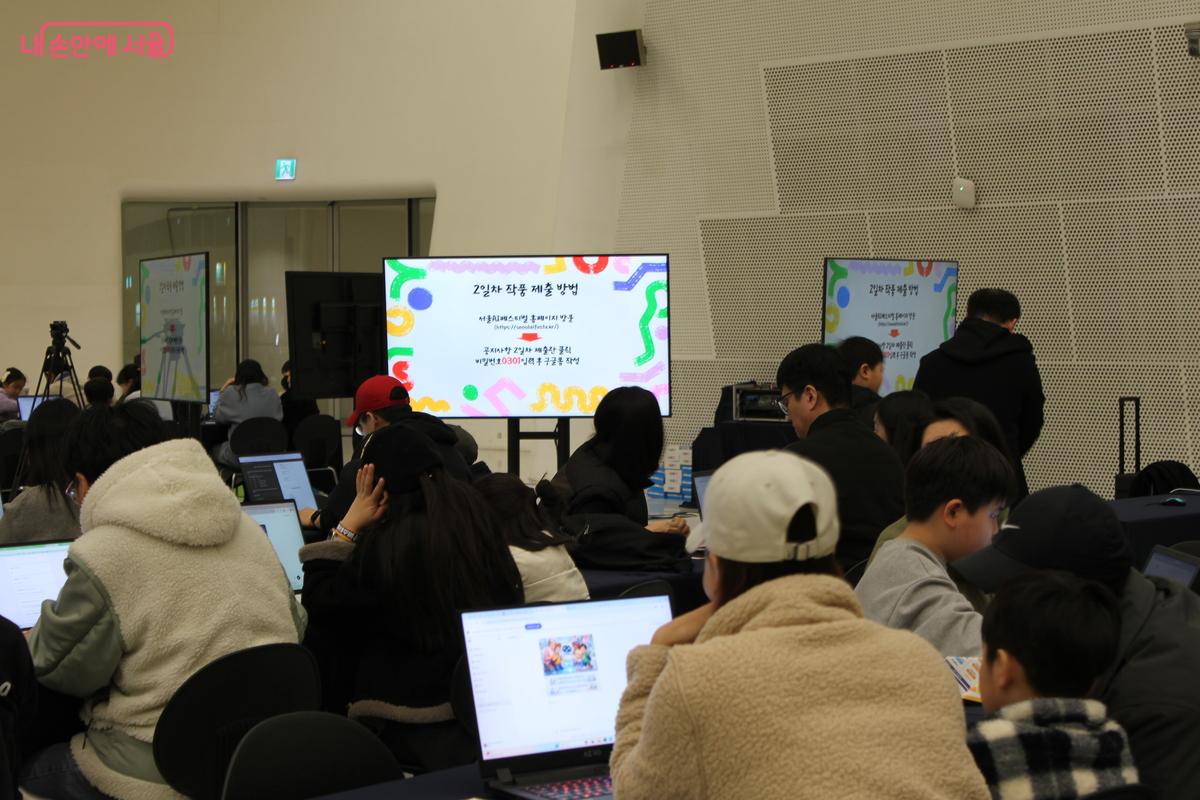 제공된 노트북과 함께 AI 서울 백일장에 참여하고 있는 관람객들