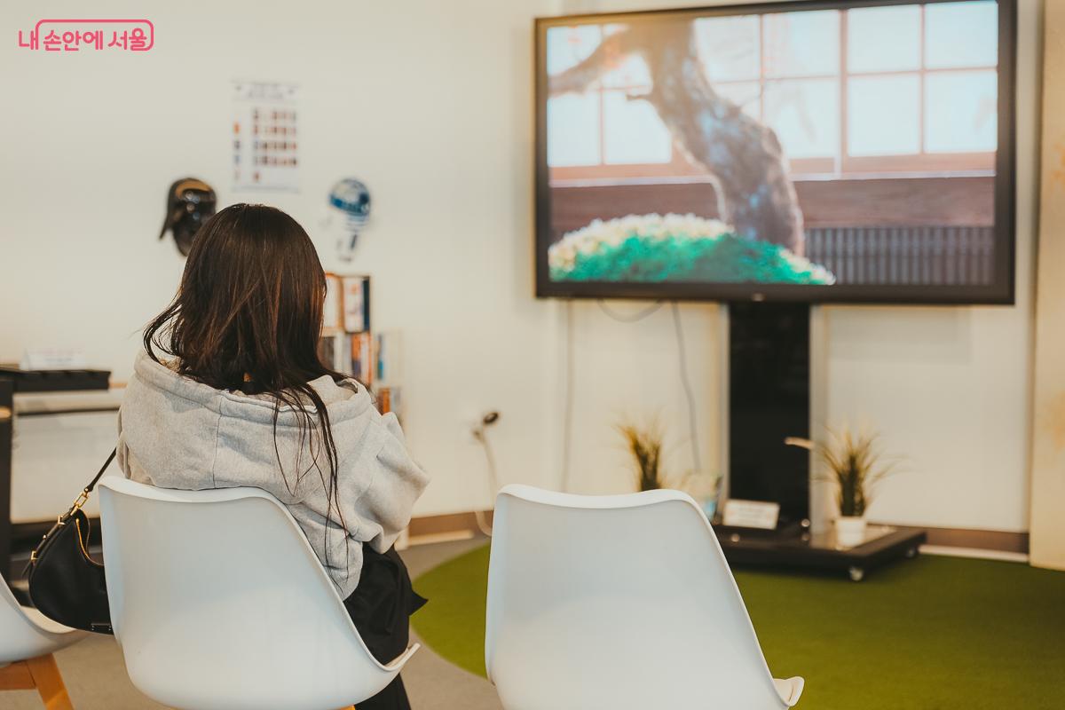 대형 모니터 앞에 놓인 의자에 앉아 애니메이션을 관람하는 시민 &copy;김성무