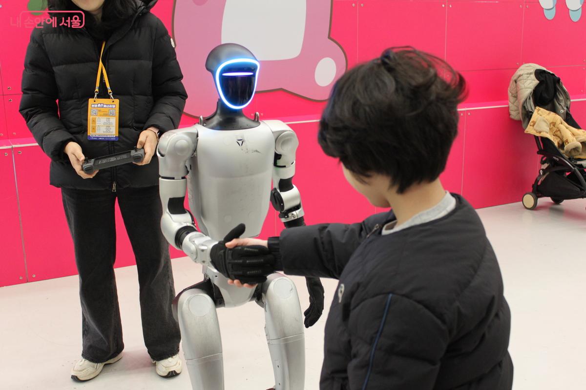 휴머노이드 로봇과 악수하는 어린이 관람객