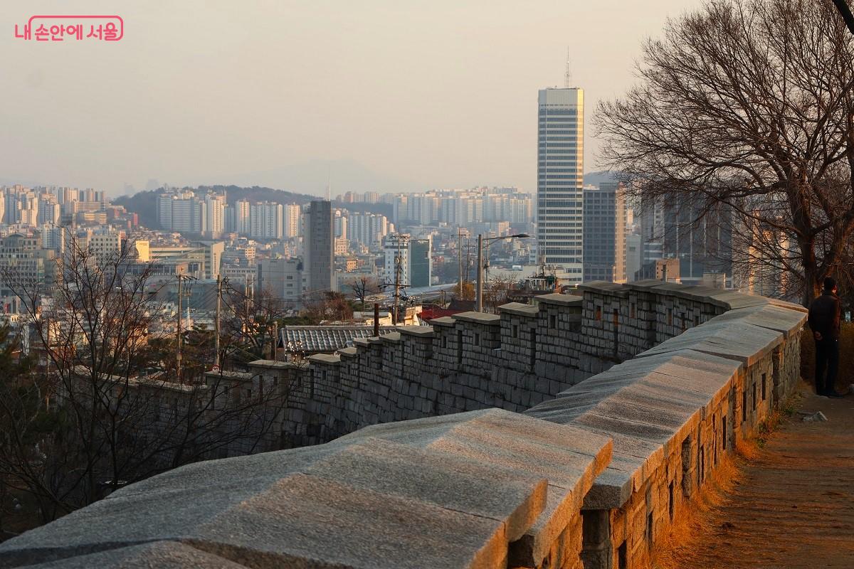 노을빛에 물든 성곽 곡선 너머로 서울 도심의 전경이 고즈넉하게 펼쳐진다. &copy;이봉덕