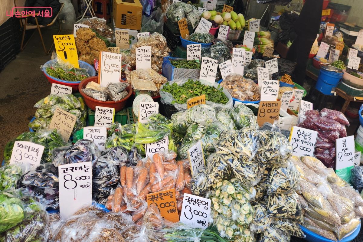 남구로시장 한 채소가게에 우엉, 고구마순, 서리태, 가지, 도라지 등 다양한 채소가 진열돼 있다. 일부는 투명 봉지에 소분돼 있고, 일부는 큰 다라이에 담겨 판매되고 있다.