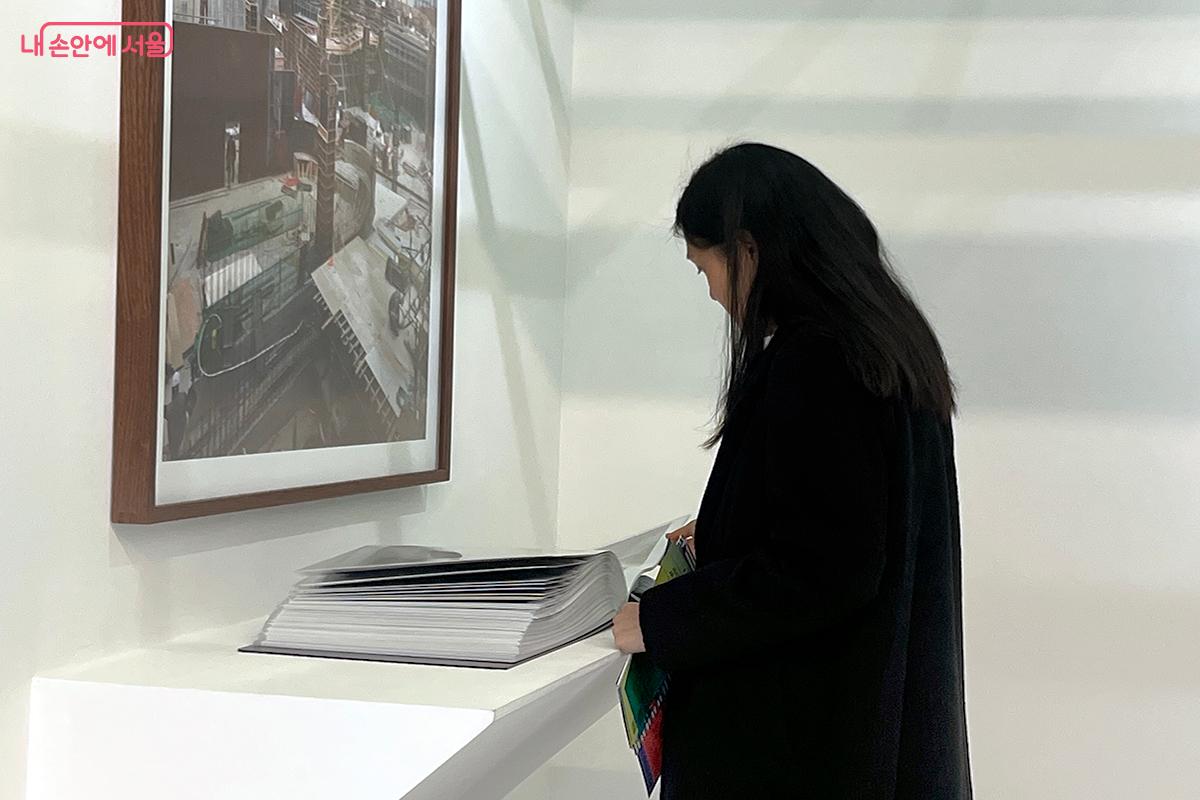 서서울미술관 건립기념 프로젝트를 담은 책자를 살펴보고 있다 ⓒ이다현