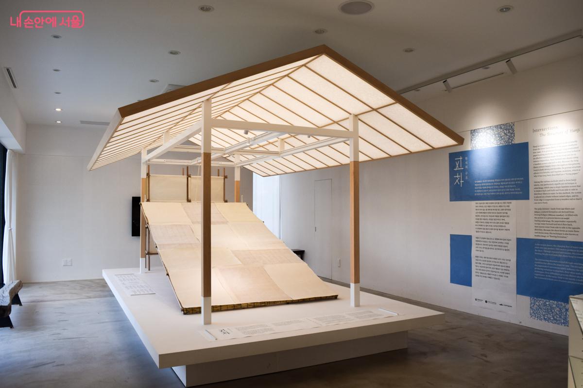 1층 중앙의 한지마루에 설치된 <교차:한지의 구조> 전시물, 한지 제작 도구를 확장한 '외발' 전경 ⓒ이명은