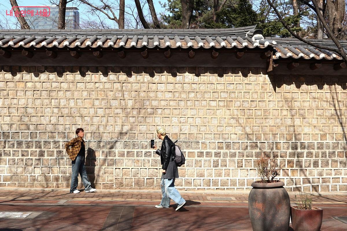 봄볕이 내리쬐는 덕수궁 돌담길에서 시민들이 일상의 여유를 즐기는 모습을 볼 수 있다. &copy;이봉덕