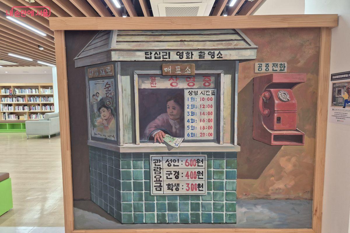 1970년대 영화매표소를 재현해놓은 그림앞에서 영화배우가 되어 영화티켓을 사는 장면을 사진찍어 보세요