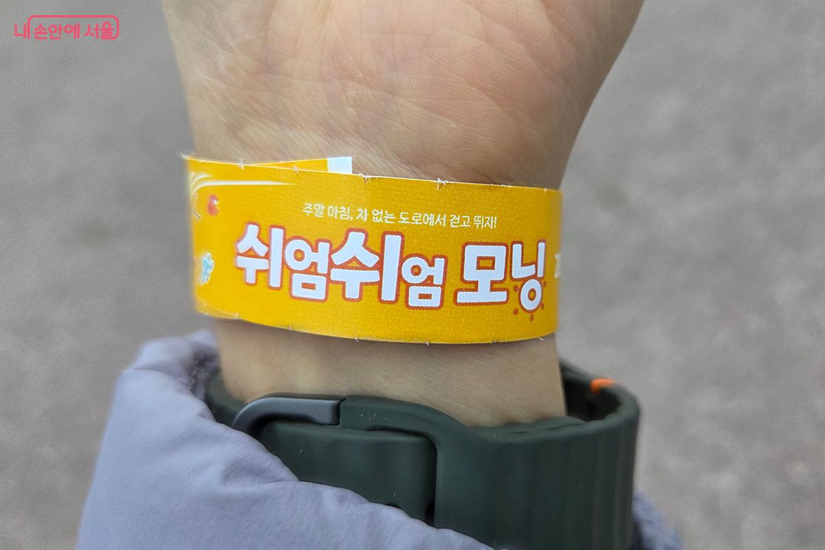 '쉬엄쉬엄 모닝' 참가자임을 나타내는 노란색 종이 팔찌를 착용한 모습 &copy;이다현