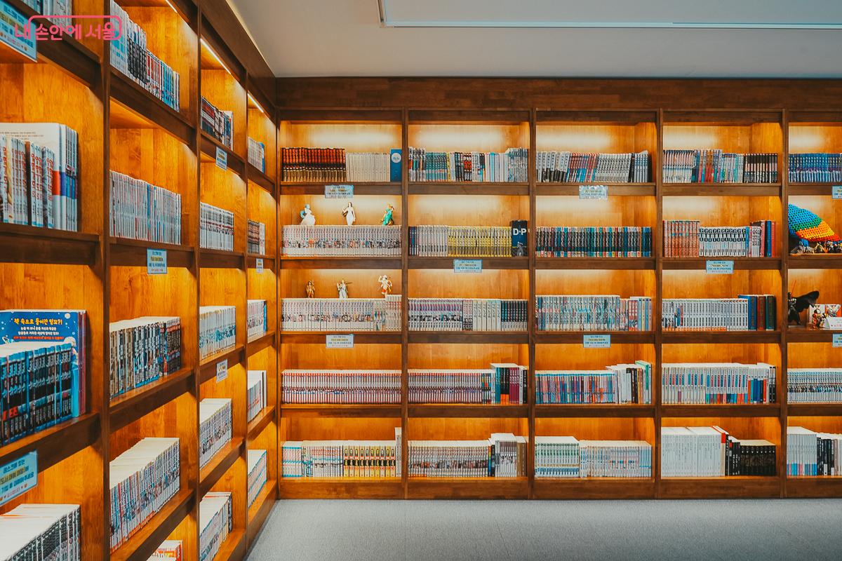 층고가 높은 벽면을 가득 채운 대형 원목 만화책 서가 전경 &copy;김성무