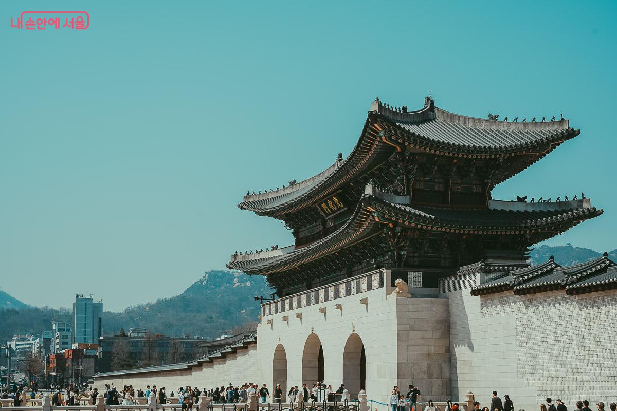 맑은 하늘 아래 사람들이 오가는 광화문의 웅장한 외부 전경 사진