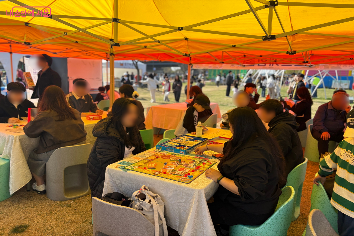 시민들이 보드게임 부스에 둘러 앉아 보드게임을 즐기고 있는 모습