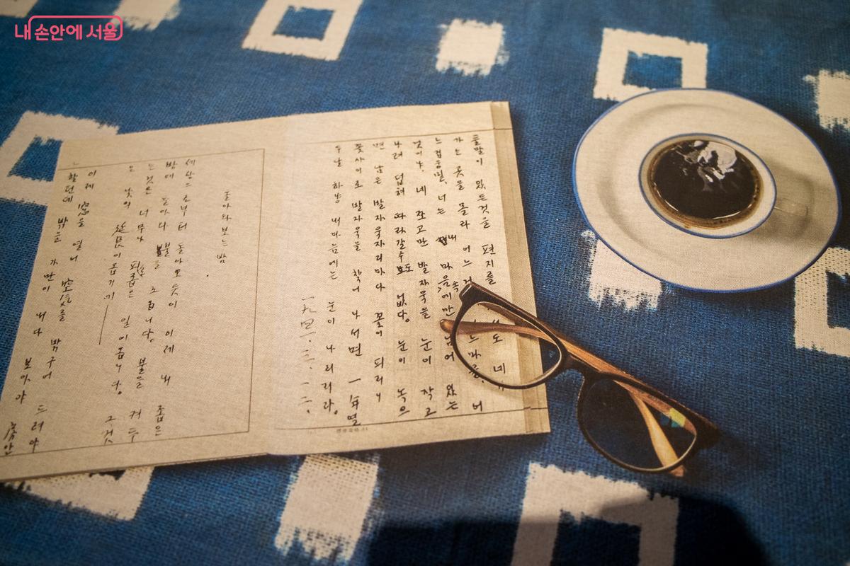 시인의 일상에 함께하는 기분으로 테이블보에 프린트된 노트와 안경, 찻잔 &copy;이란