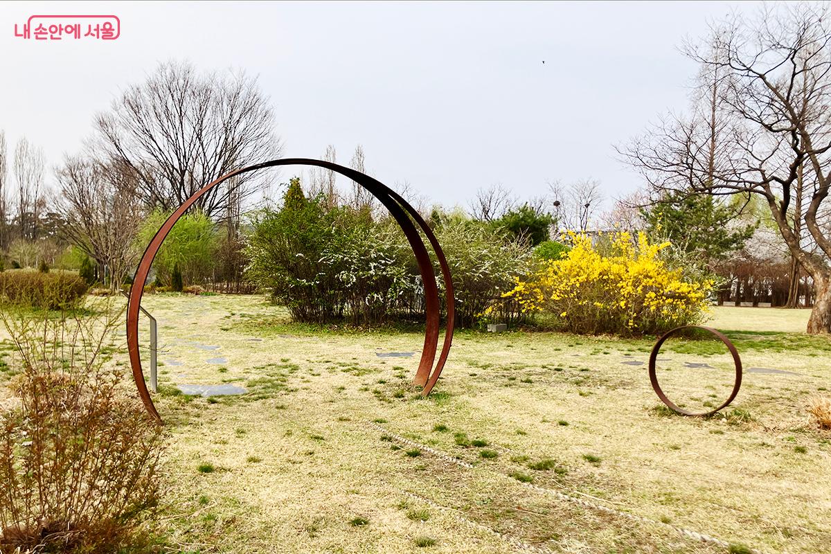 푸른 잔디밭 위, 화사한 봄꽃과 어우러진 원형 조형물 ©이란