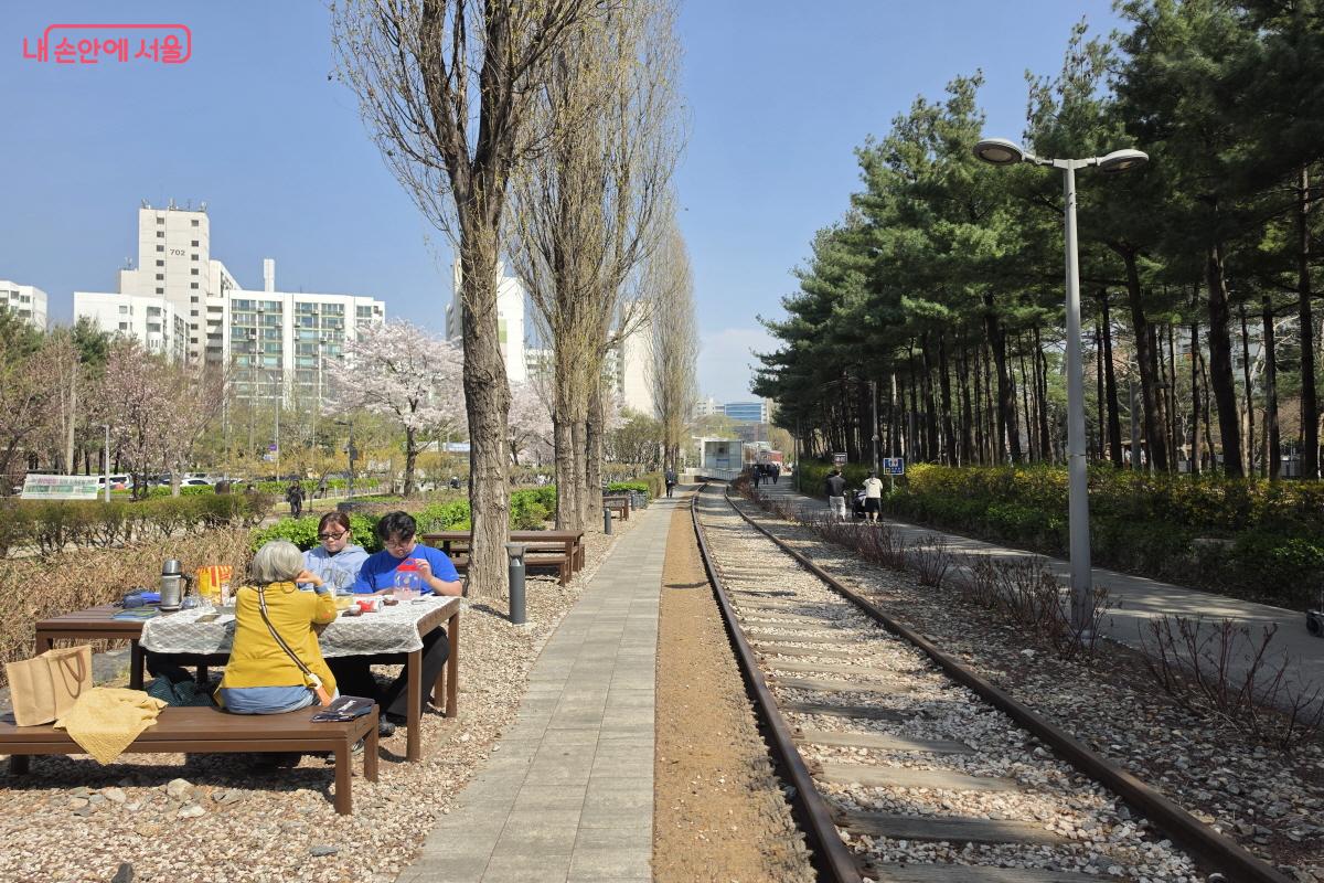 철로 옆에 놓인 테이블에서 피크닉을 즐기는 시민들.