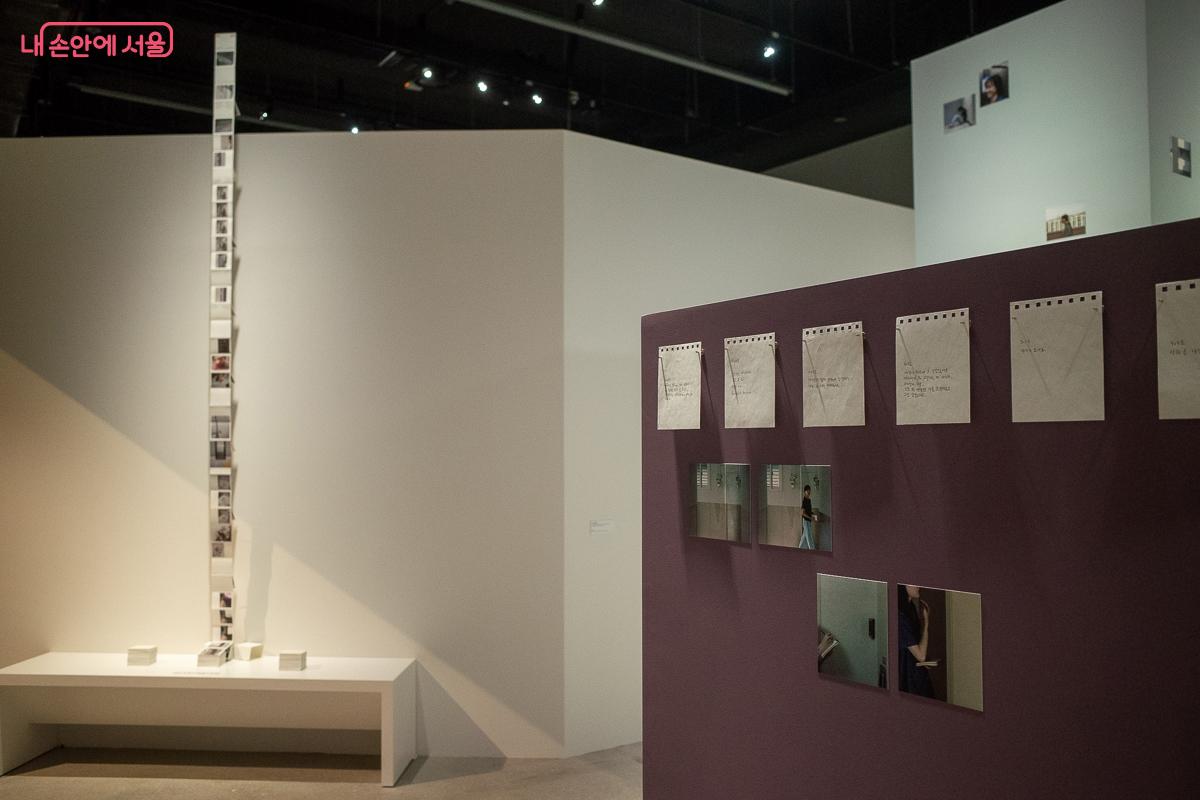 배경의 수직 사진 탑이 기록의 방대한 양을 시각화하고, 메모와 작은 사진이 기둥을 이룬다. &copy;이란