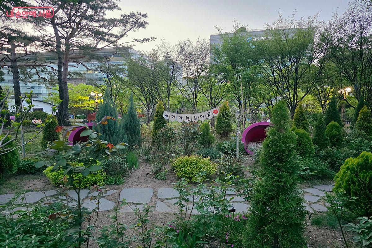 "내가 가는 길이 꽃", "너와 나의 정원" 같은 따뜻한 문구 가랜드와 분홍 원형 프레임이 예쁜 시민참여형정원 &copy;이정민