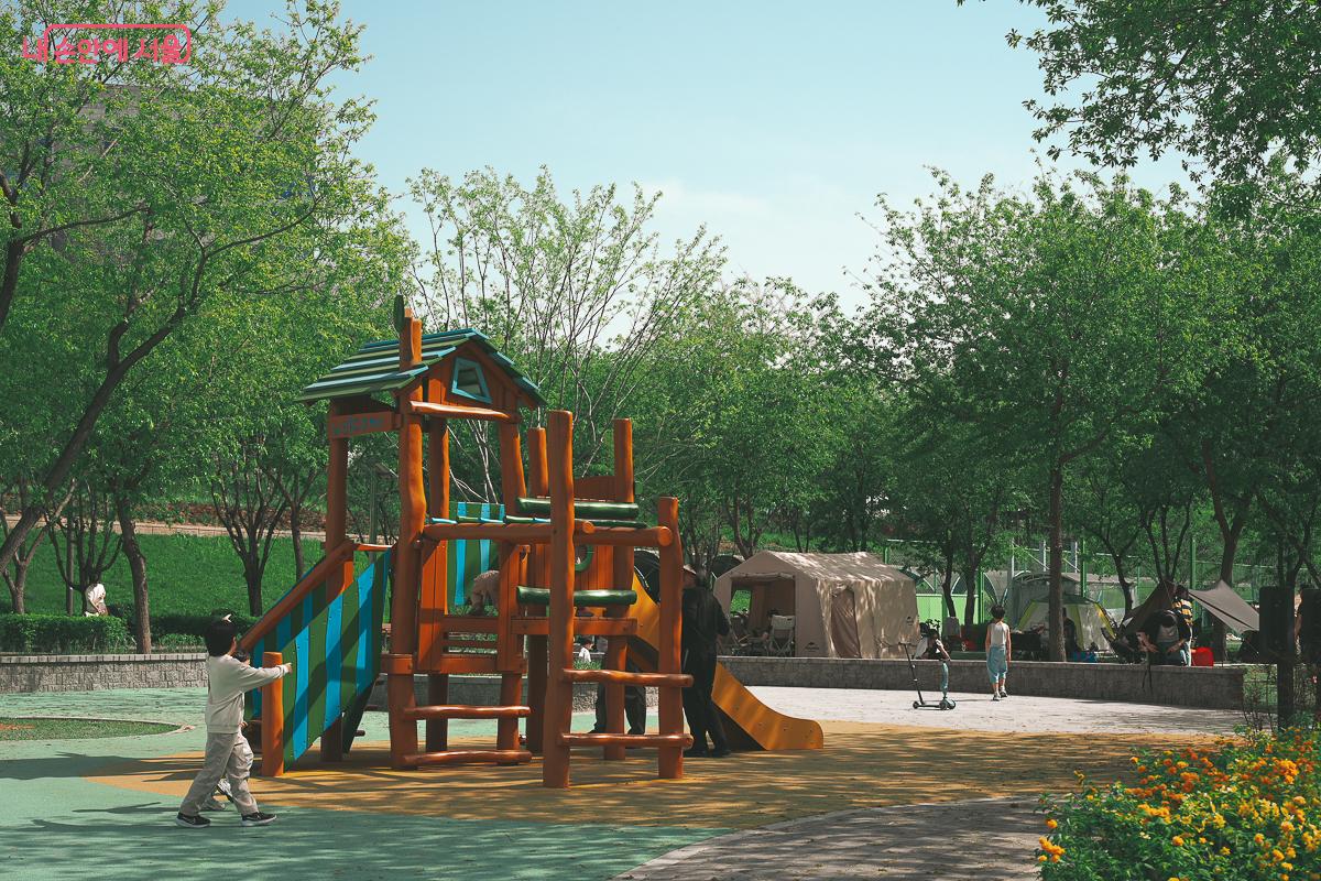 잔디밭과 텐트들을 배경으로 나무 오두막 모양의 미끄럼틀과 놀이 기구가 설치되어 있고 아이들이 뛰어놀고 있다. &copy;김성무