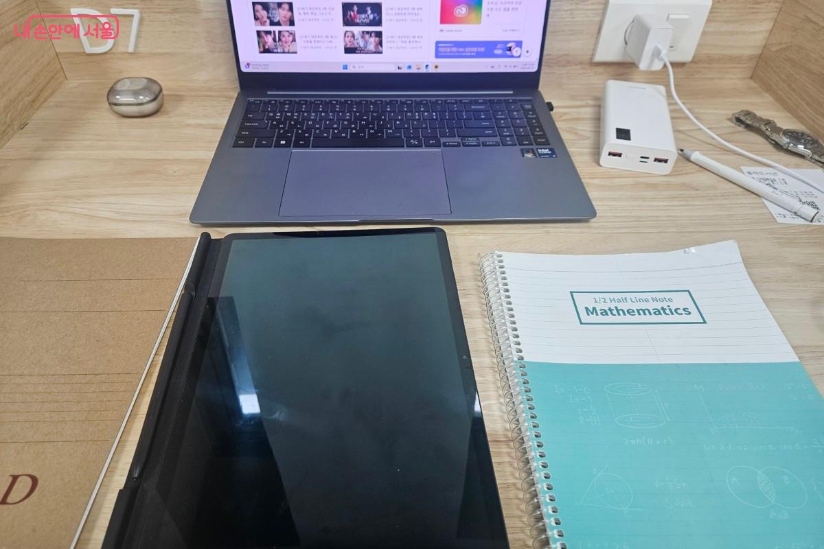 서울시민기자가 실제 디지털학습실을 이용하고 찍은 사진이다. D7 좌석에서 노트북, 태블릿PC, 공책. 보조배터리, 충전기 그리고 손목시계가 자리에 있다.