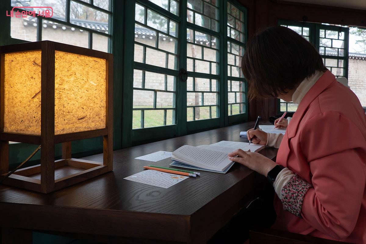 팔우정에서 필사 체험 중인 참가자. 엽서와 노트에 글이 가득하다. &copy;김인수