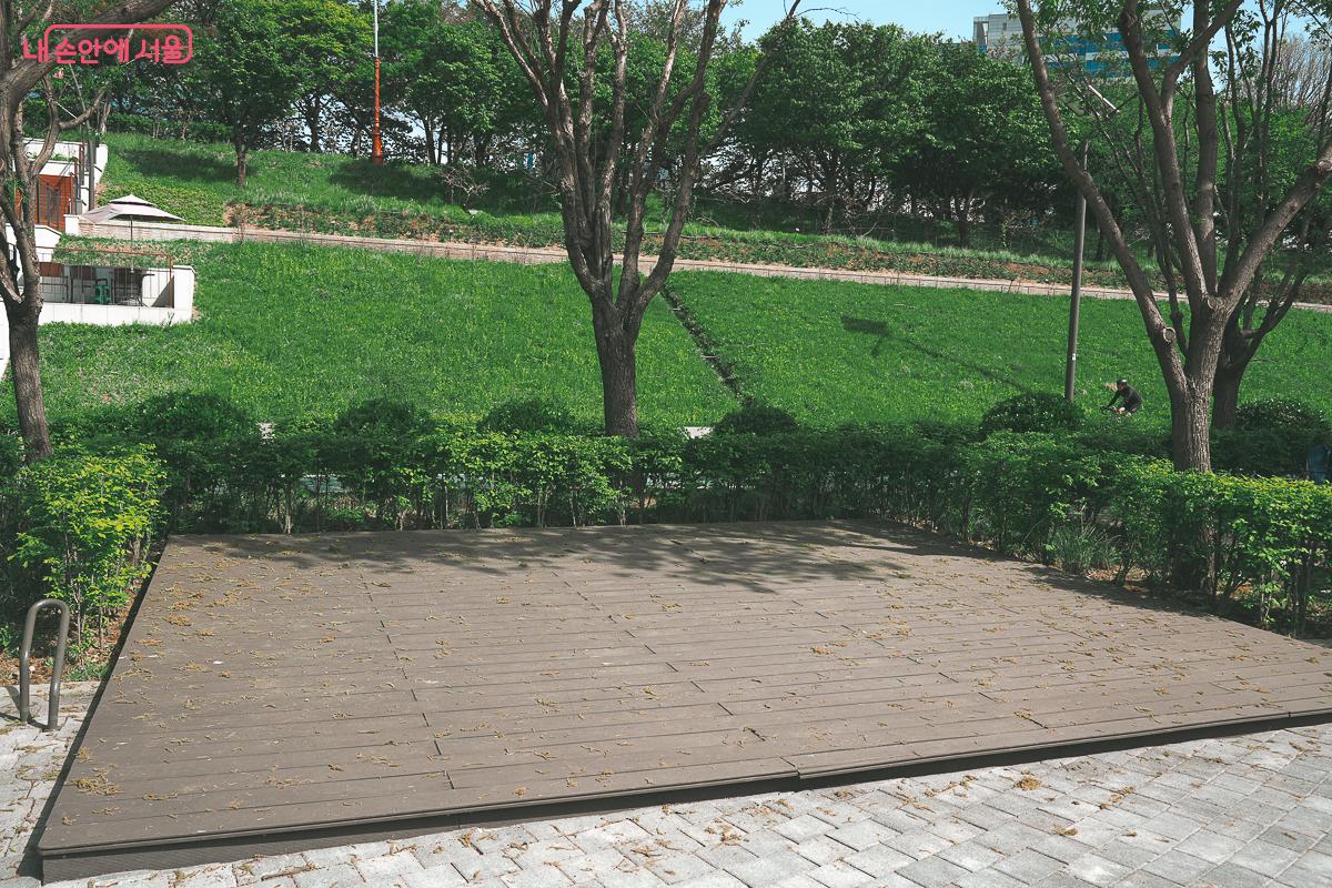 푸른 나무와 잔디를 배경으로 텐트를 치거나 휴식을 취할 수 있도록 바닥에 설치된 넓고 평평한 나무 데크 &copy;김성무