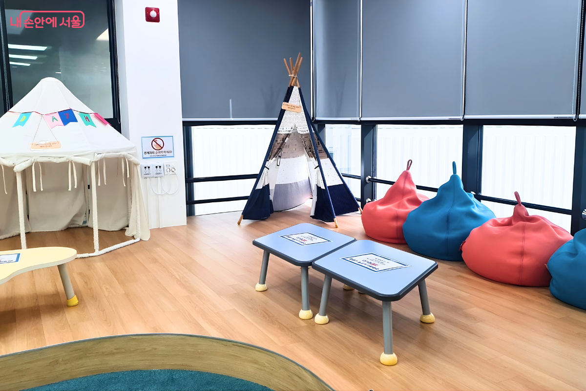 어린이들이 자유롭고 편안하게 책을 읽을 수 있도록 조성된 5층 제2열람실의 마루 공간이다. 신발을 벗고 이용하는 마루 위에는 아이들의 호기심을 자극하는 하얀색 인디언 텐트와 알록달록한 빨간색, 파란색 빈백 소파가 배치되어 있다. 창가 쪽으로는 낮은 테이블들이 놓여 있어 아이들의 눈높이에 맞춘 아늑한 독서 환경을 제공한다.
