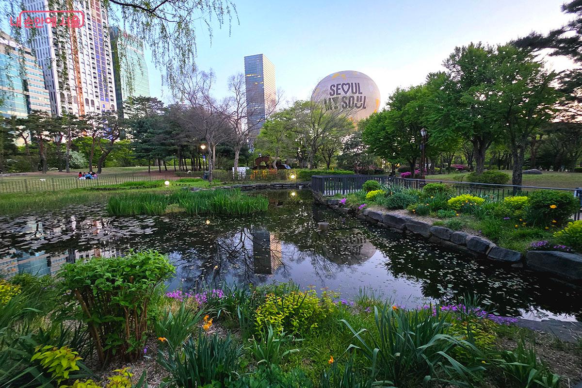 봄꽃이 활짝 핀 여의도공원 잔디마당 연못과 상공에서 도심 풍경을 즐길 수 있는 서울달 &copy;이정민