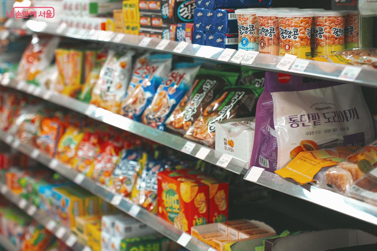 편의점 진열대에 각종 과자와 빵 땅콩 등 다양한 종류의 간식들이 빼곡하게 진열되어 있는 근접 촬영 사진