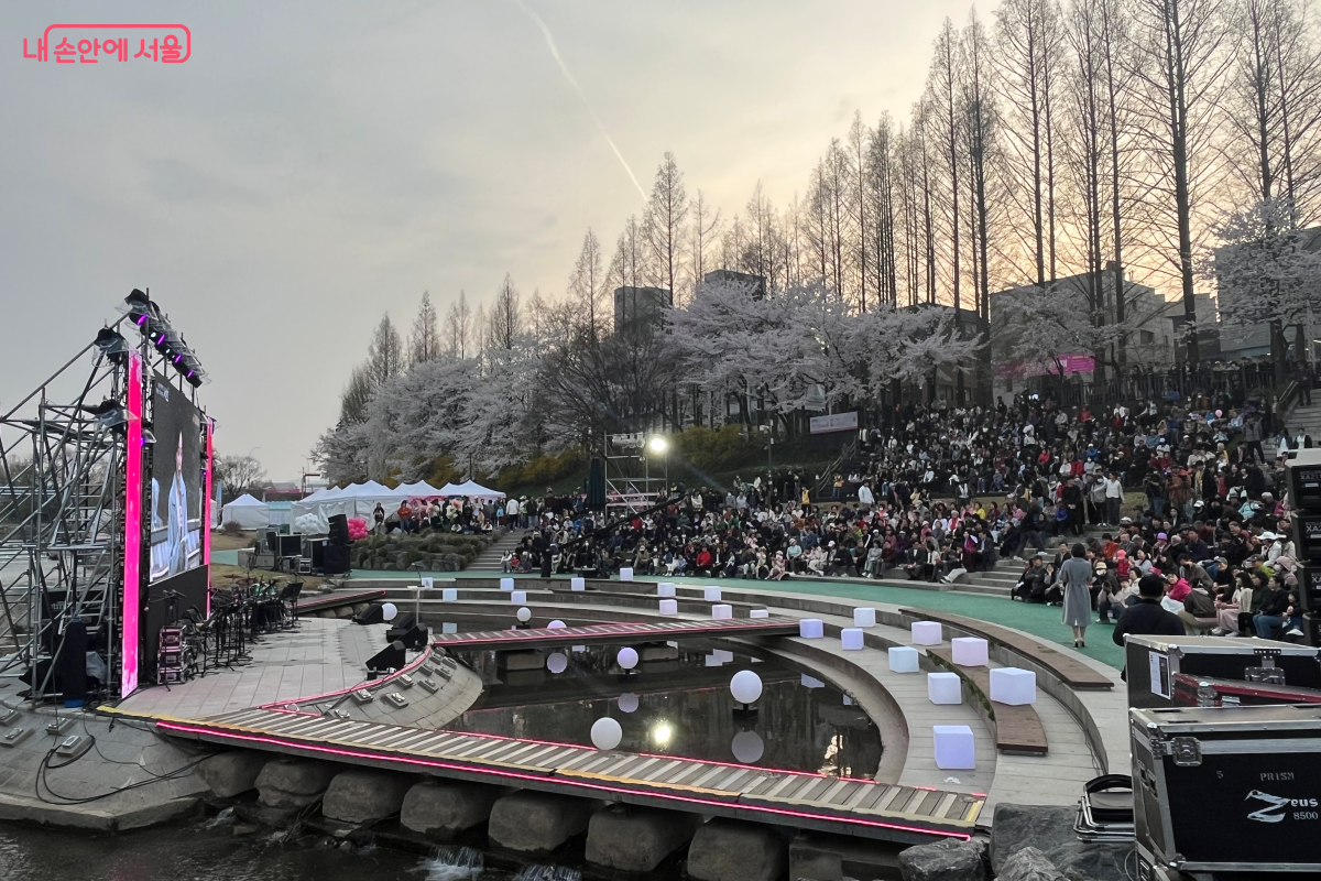 흩날리는 벚꽃 아래, 봄밤의 설렘을 함께 나누는 시민들로 수변무대가 가득하다. &copy;김연희