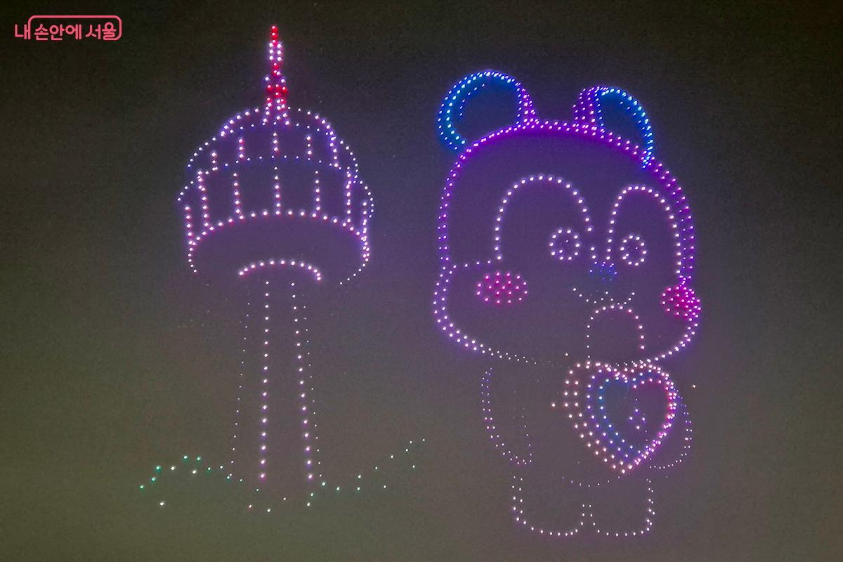 드론으로 남산 타워 옆에서 포즈를 취하고 있는 캐릭터를 표현하고 있다.