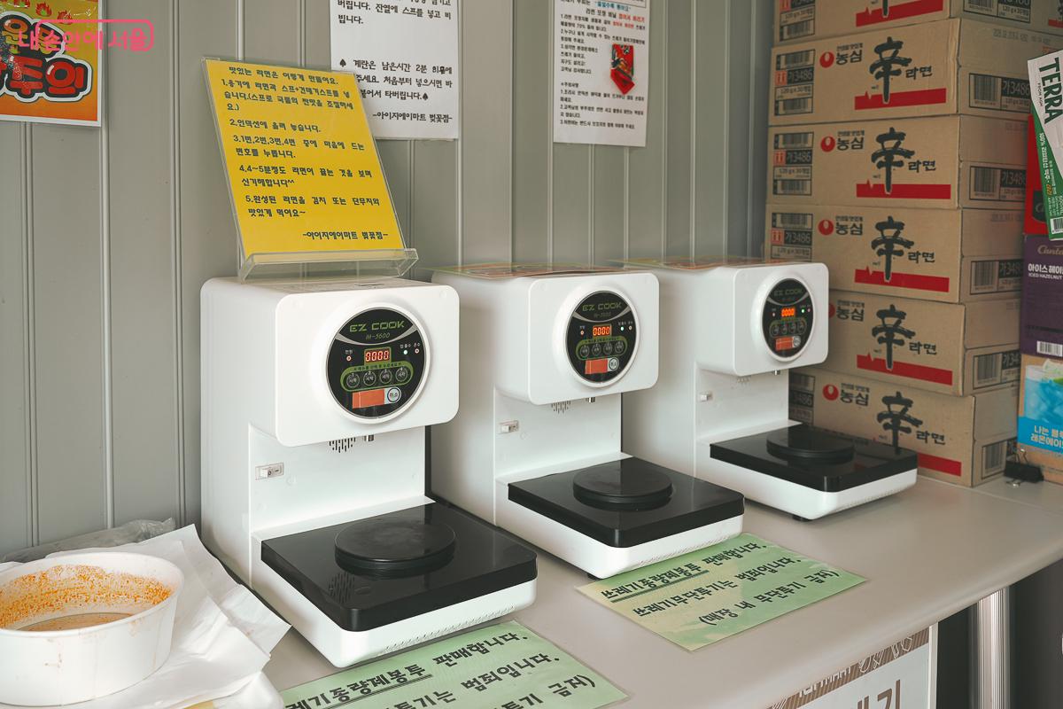 편의점 실내 테이블 위에 은박지 그릇을 올려놓고 끓일 수 있는 하얀색 즉석 라면 조리기 3대가 나란히 설치된 모습 &copy;김성무