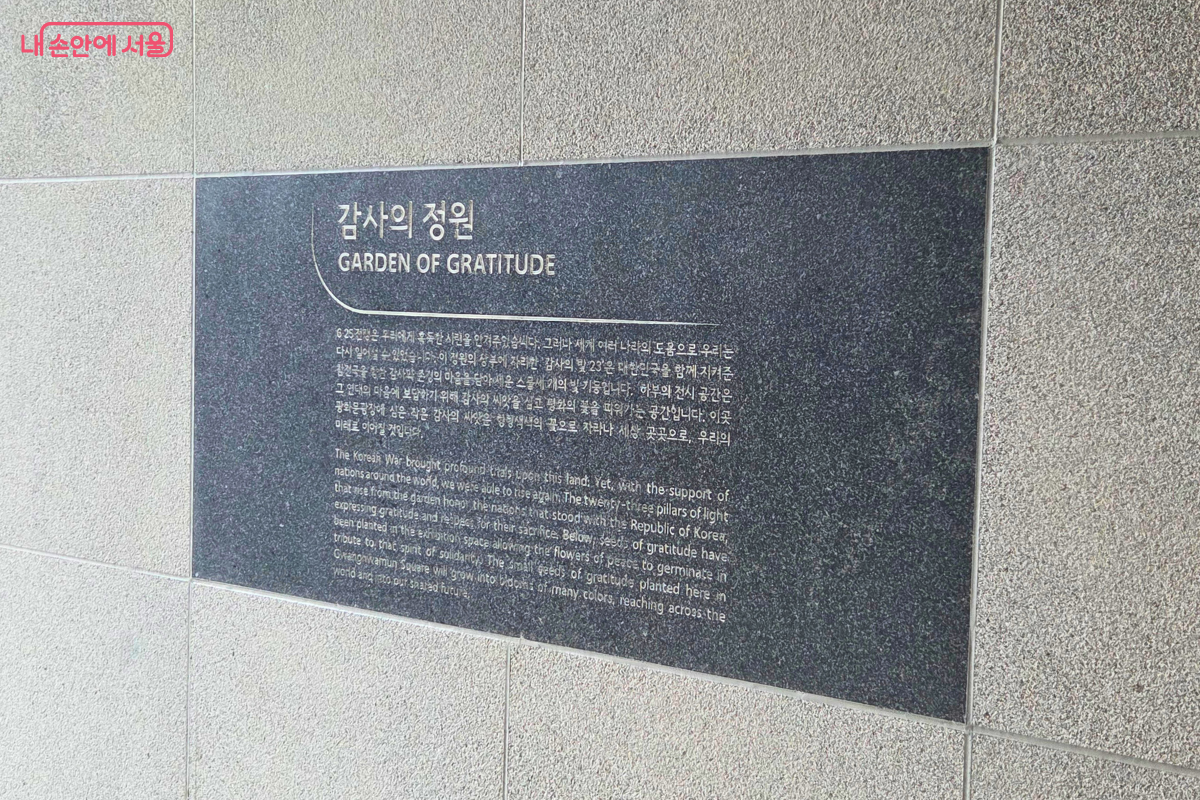 프리덤 홀 입구 벽면에 &lsquo;감사의 정원&rsquo;이라고 적힌 검은 안내석이 설치되어 있고, 아래에는 감사의 정원 조성 의미를 설명하는 한글과 영어 안내문이 새겨져 있다.