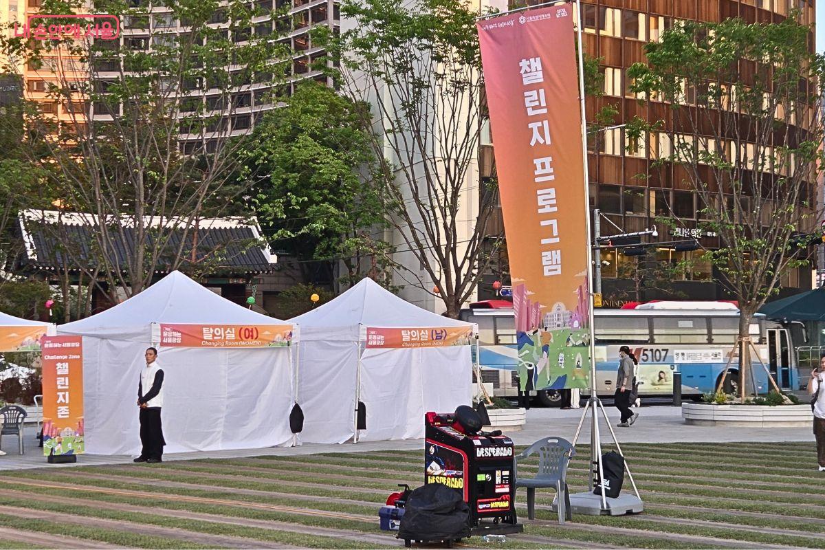 서울광장 행사장 한편에 &lsquo;챌린지 프로그램&rsquo; 세로 배너와 남녀 탈의실 천막이 설치되어 있다. 주변에는 행사 장비와 안내 표지판이 놓여 있어 참여자를 위한 부대시설이 마련된 모습이다.