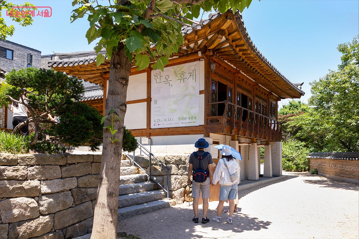 무계원 사랑채 외벽에 게시된 한옥 휴게 프로그램 안내문을 살펴보는 방문객