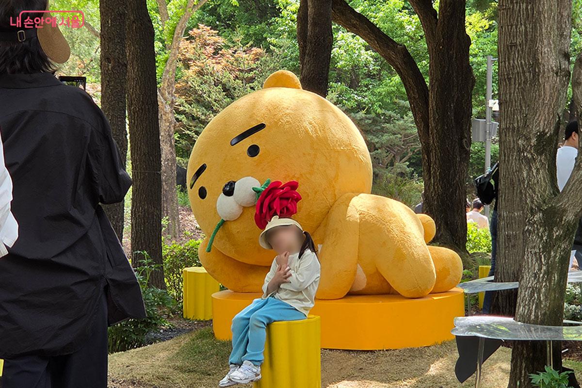 장미꽃을 입에 문 대형 라이언 조형물 앞에서 포즈를 취하는 어린이 관람객 &copy;이다현