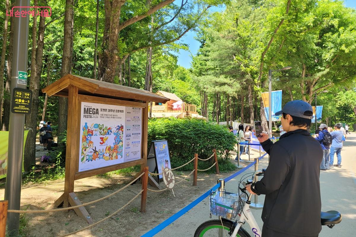 포켓몬 체험 공간 안내판과 QR 정보를 확인하며 서울숲 체험형 정원을 즐기고 있다. ©조연