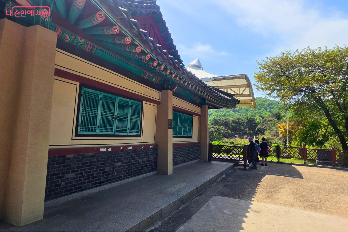 남산 숲길 옆에 자리한 석호정 한옥 외관이다. 오른쪽으로는 남산 숲과 산책로, 방문객들의 모습이 함께 보인다.