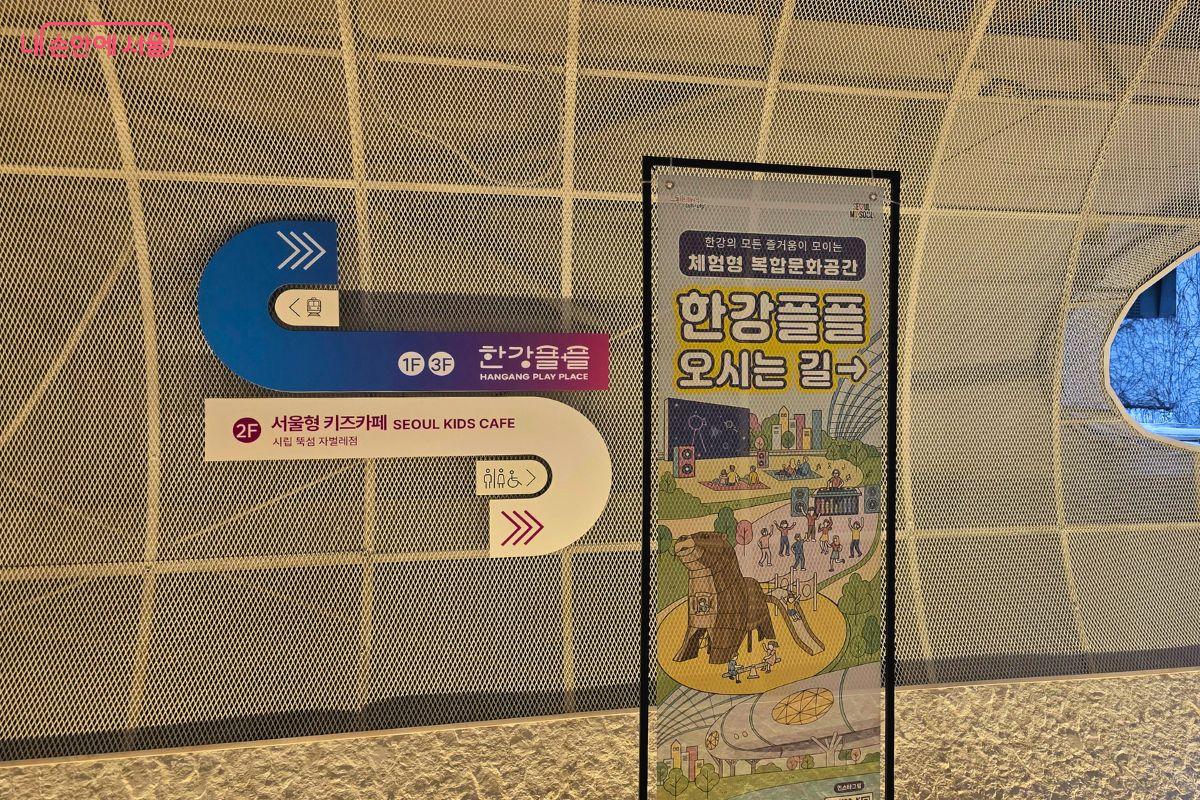 지하철 3번 출입구와 한강플플로 이어지는 파크뷰 라운지 공간이다. 벽면에는 한강플플 1층과 3층, 서울형 키즈카페, 화장실 방향을 알리는 안내 표지가 있고, 옆에는 ‘한강플플 오시는 길’ 안내판이 세워져 있다.