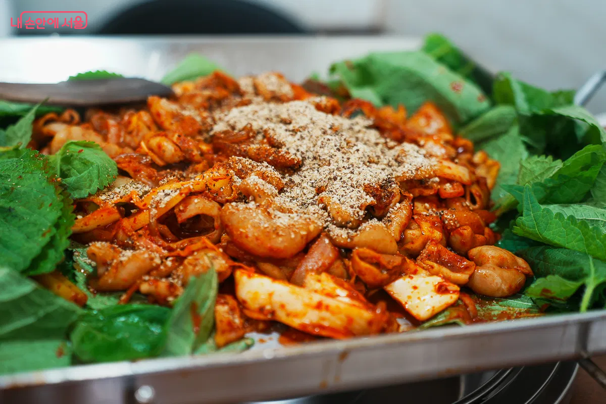 철판 위 곱창볶음, 깻잎과 함께 볶아진 곱창과 채소, 들깨가루 뿌린 완성 직전 모습