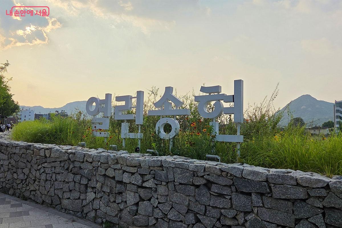 푸른 잔디와 봄꽃 너머로 인왕산 자락이 한눈에 들어오는 열린송현녹지공간 입구 ⓒ이다현