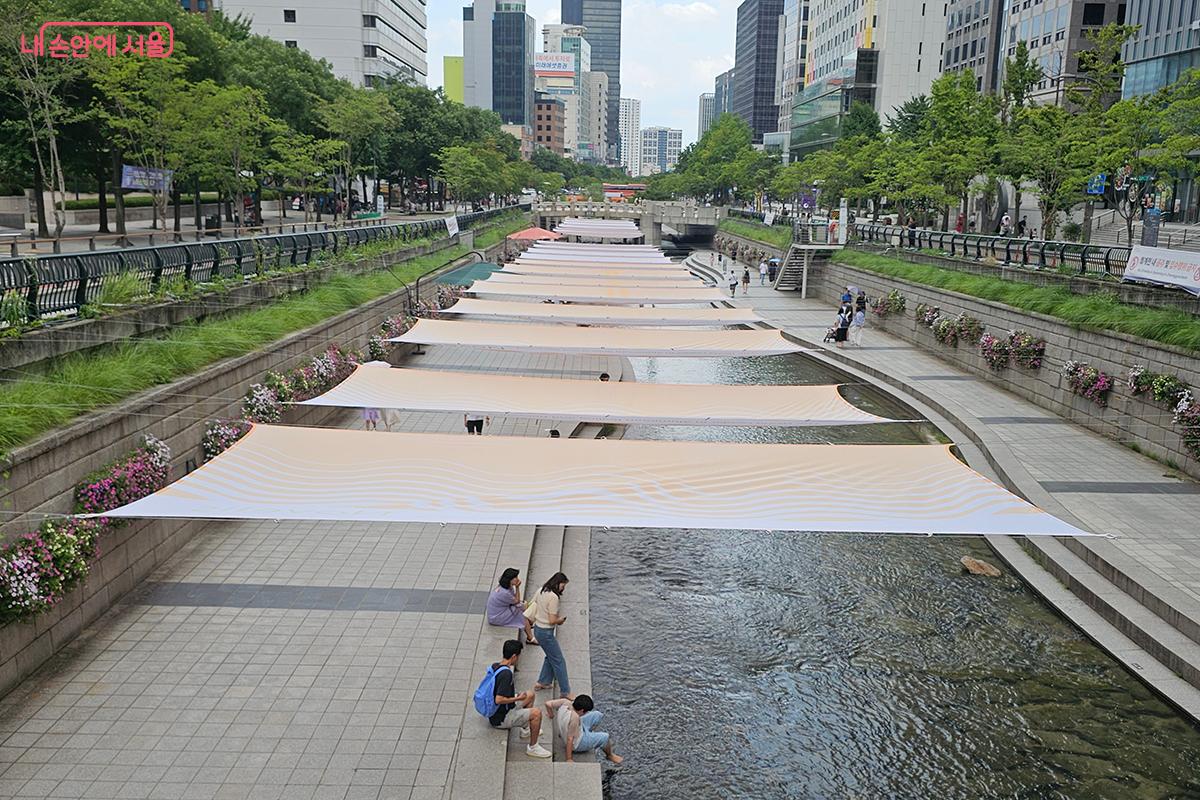 강렬한 햇빛을 막아주는 그늘막과 활짝 핀 꽃들이 어우러진 청계천 ⓒ오도연