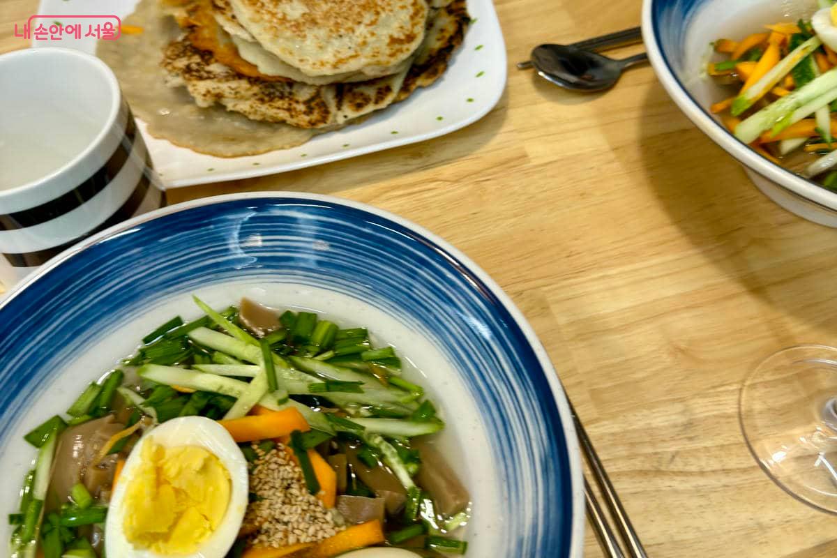 차게 식힌 육수에 도토리묵과 오이, 김치를 올린 묵사발과 갓 부친 감자전 ©유빈