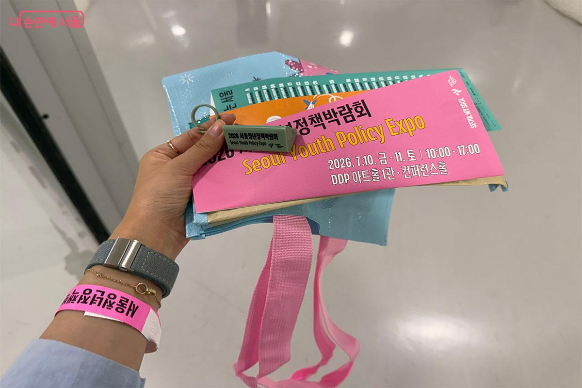 박람회장에 입장하는 청년에게 나눠준 팸플릿과 키링, 그리고 타포린백. ⓒ송수아