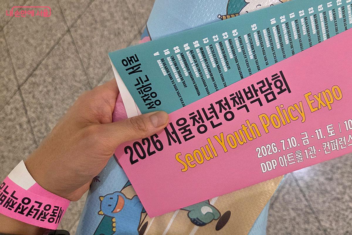 2026 서울청년정책박람회 입장을 위한 핑크색 손목띠와 행사 안내 리플릿 ©이다현