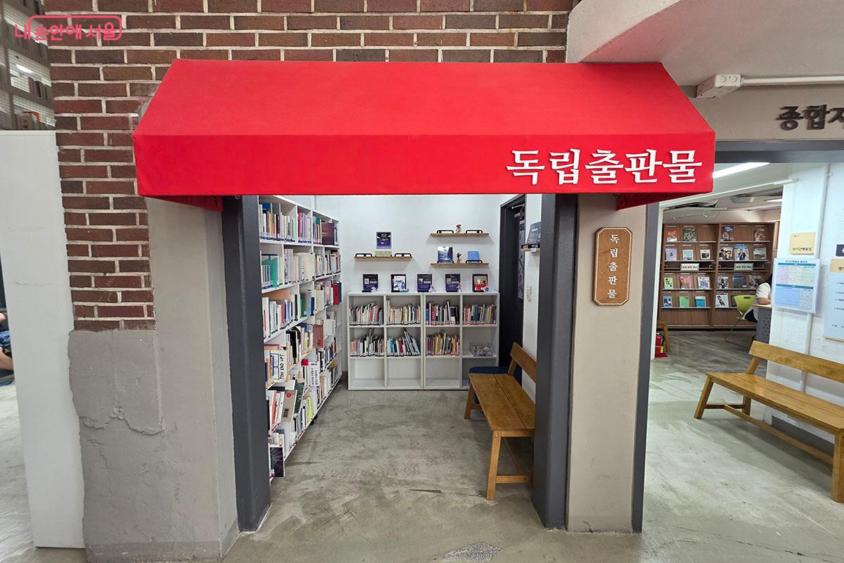 옛 주택의 붉은 벽돌 외벽과 빨간 천막 어닝을 활용해 아늑하게 조성한 독립출판물 서가 코너
