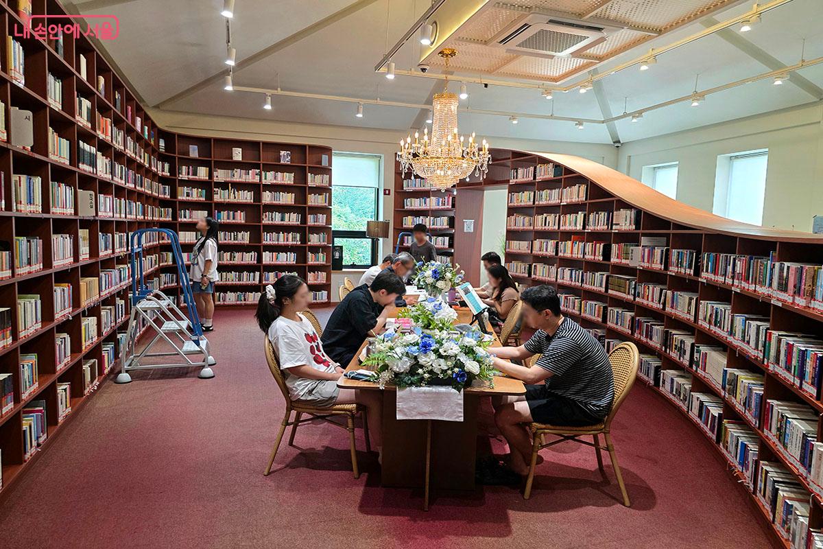 화려한 샹들리에와 곡선형 목재 서가가 돋보이는 손기정 문화도서관 내부. 시원하고 아늑한 분위기 속에서 시민들이 독서를 즐기고 있다.
