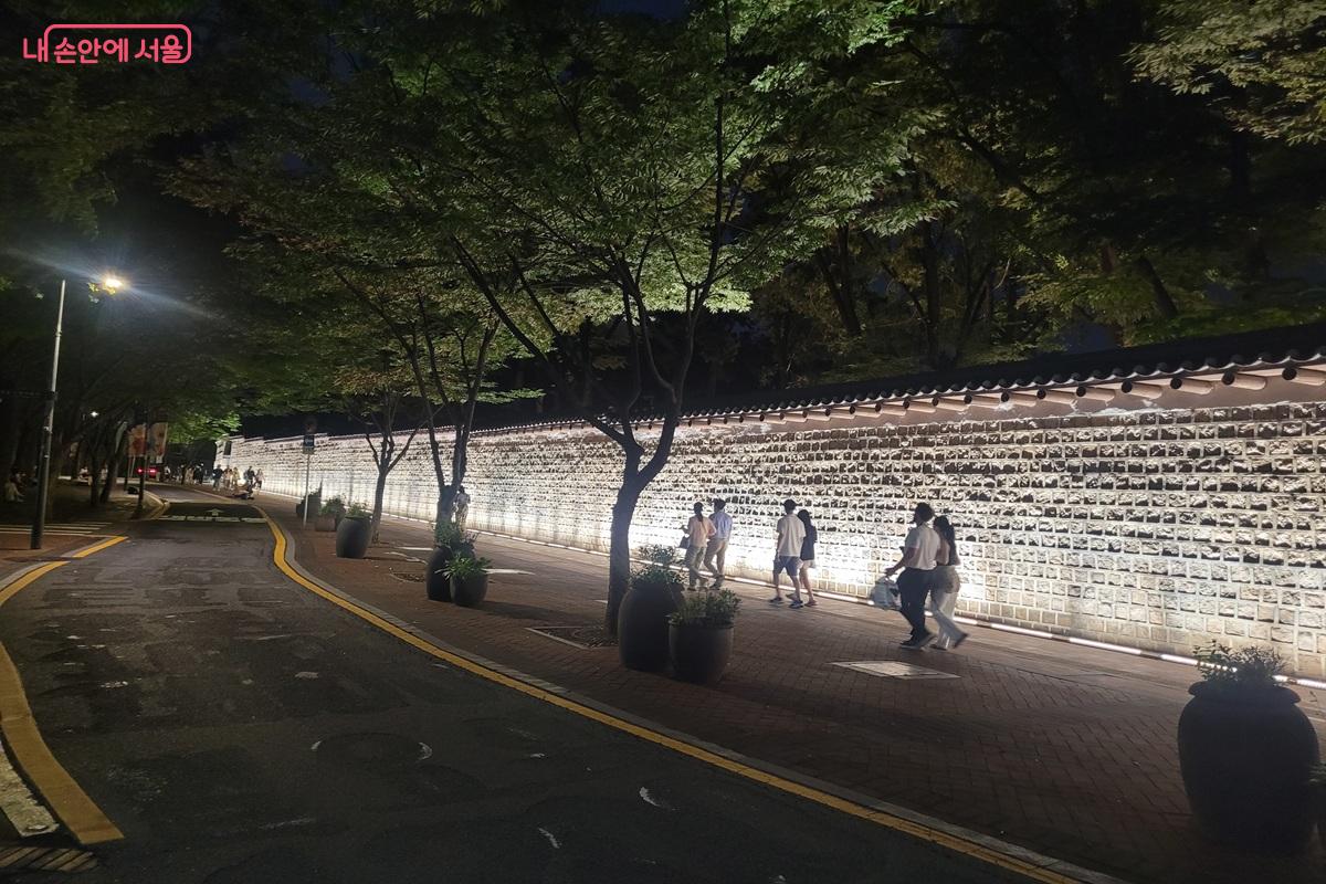 조명이 켜진 덕수궁 돌담길을 따라 시민들이 여름밤 산책을 즐기고 있다. ©조연