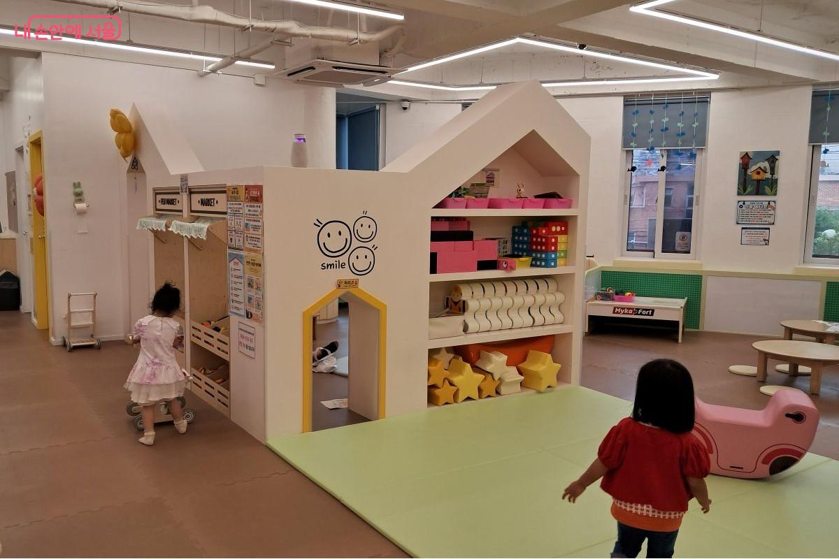 아이가 장난감 카트를 밀며 장보기 놀이를 하는 장면