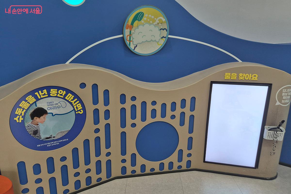 돋보기를 흰 판에 대고 여기저기 살펴보면서 물을 찾는 체험관 &lsquo;물을 찾아요&rsquo; &copy;이혜숙