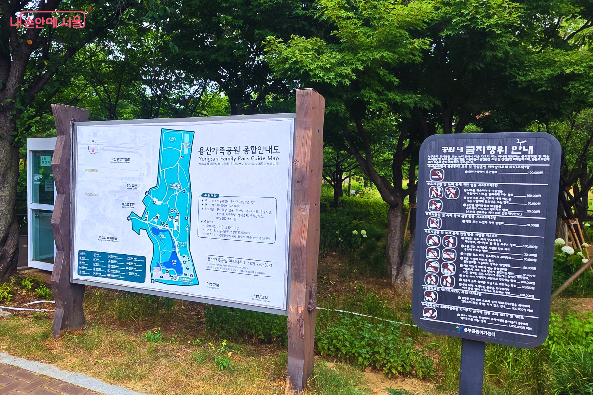 울창한 나무 아래 용산가족공원 종합안내도와 공원 내 금지행위 안내판이 나란히 세워져 있다.